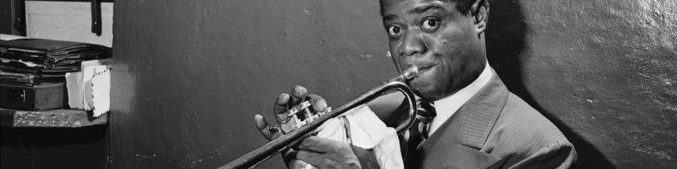 Black and white headshot of Louis Armstrong playing trumpet